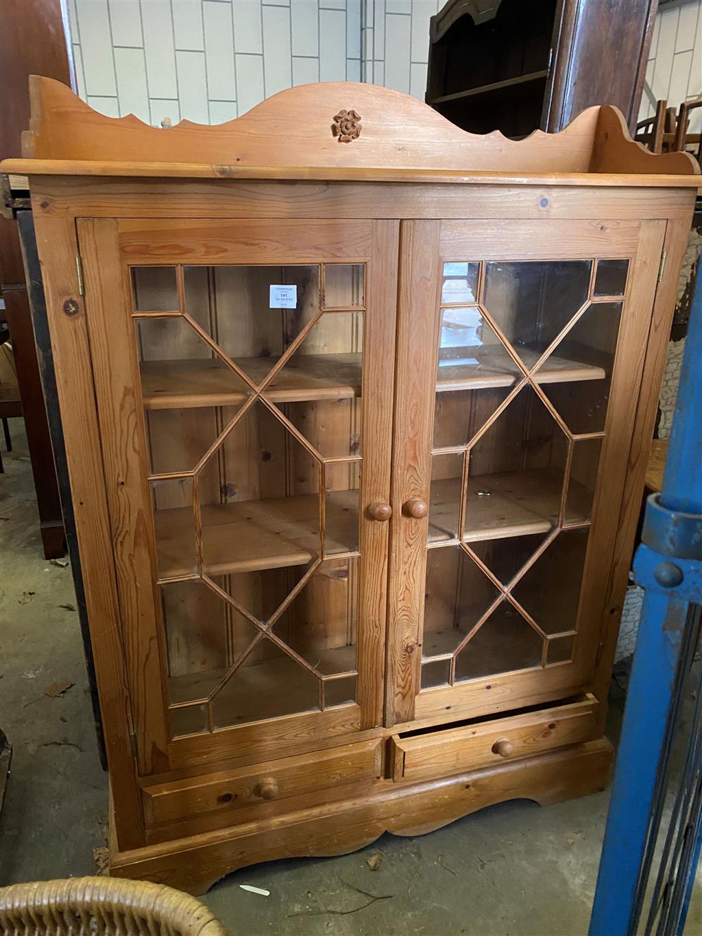 A glazed pine two door bookcase, width 112cm, depth 26cm, height 150cm